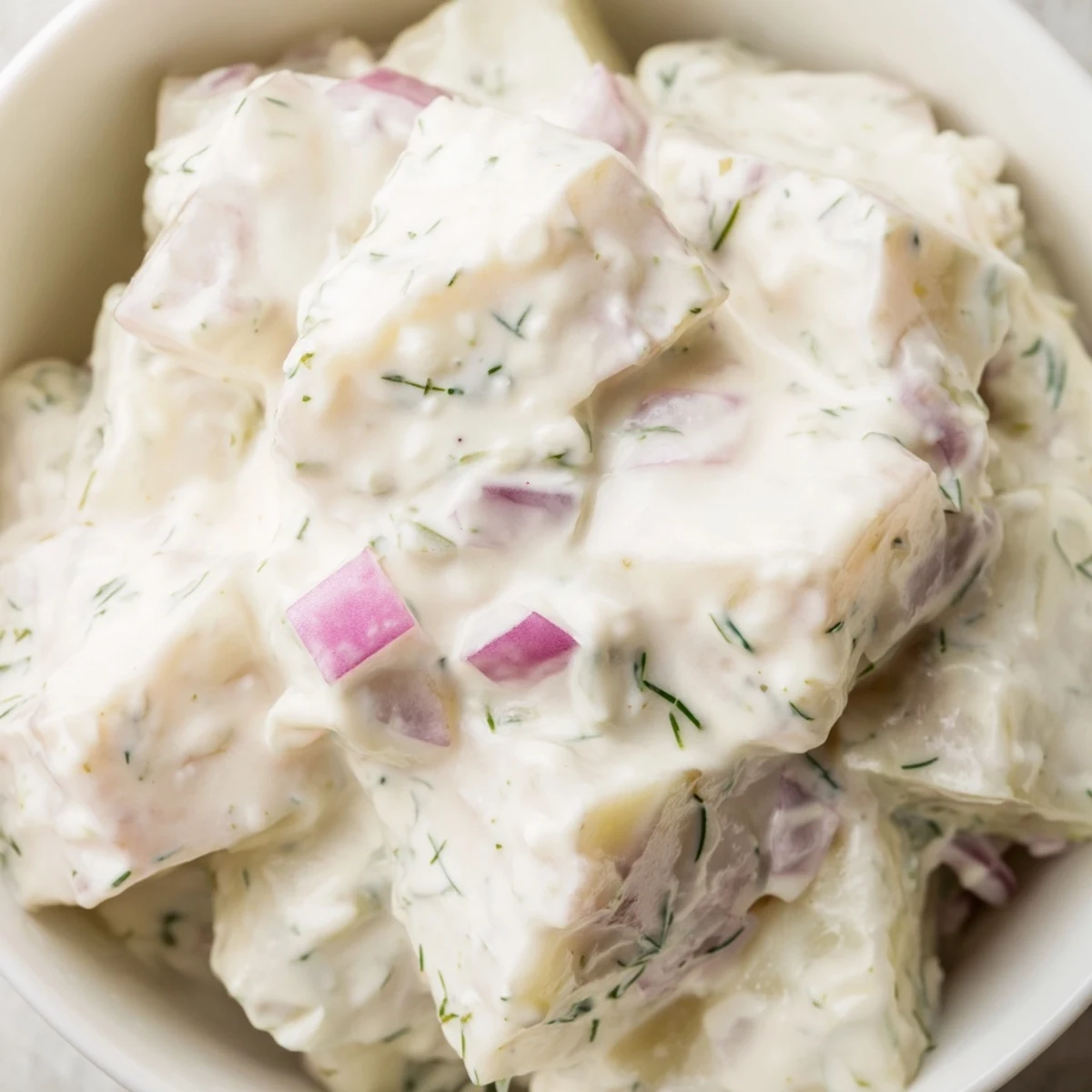 Classic Creamy Potato Salad with Fresh Dill served chilled at a summer barbecue alongside grilled burgers.