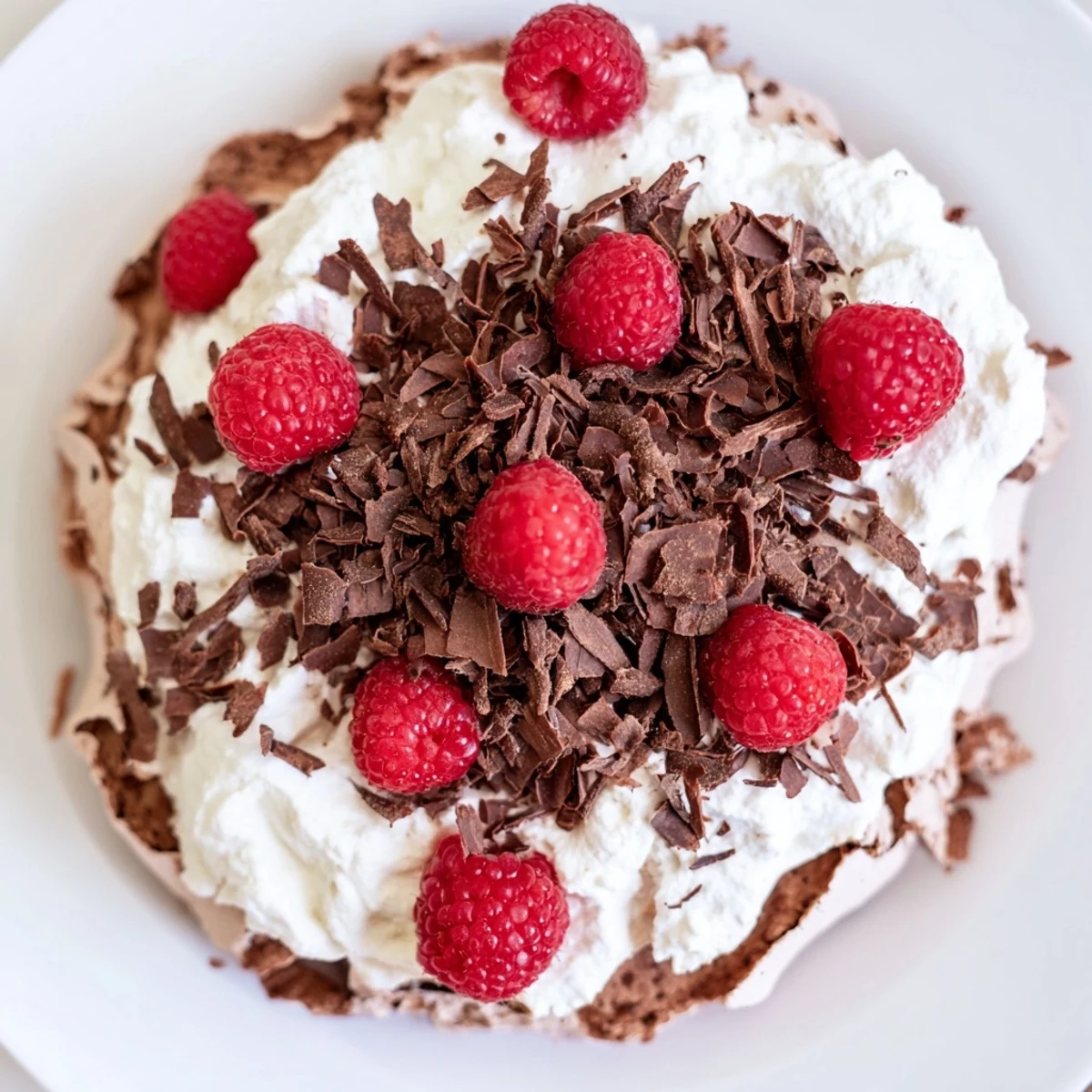Serving Chocolate Raspberry Pavlova on a platter, the crisp meringue nest holding creamy topping and vibrant berries.