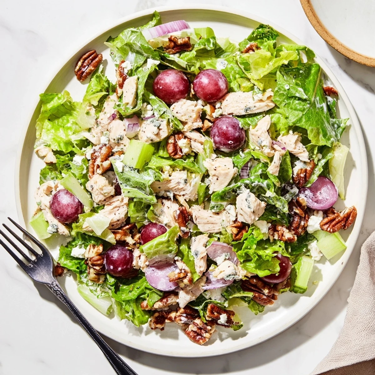 Freshly mixed Chicken Pecan Salad with Dressing features creamy homemade dressing, celery, and red onion, served on a bed of mixed salad greens.
