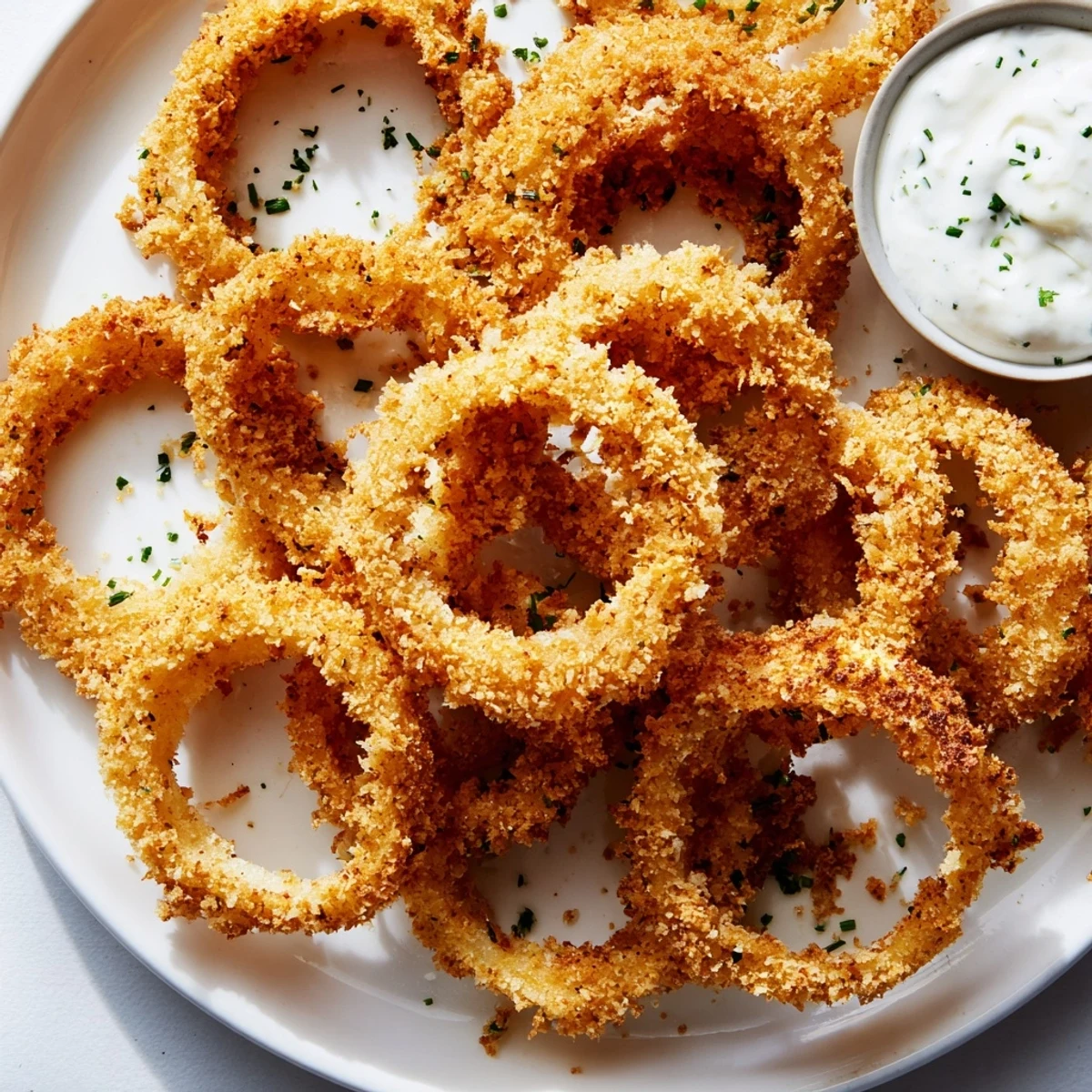 Golden-brown Touchdown Crispy Onion Rings stacked high next to a ramekin of creamy ranch dressing.  