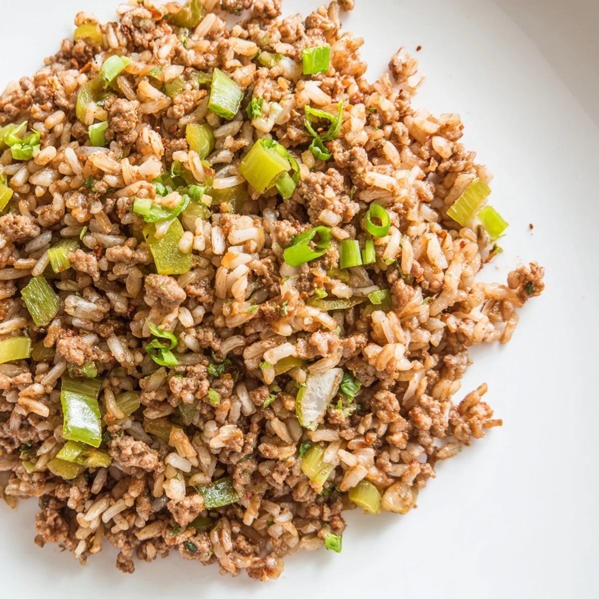 A close-up of Cajun Dirty Rice with ground turkey, featuring aromatic vegetables and fluffy rice on a rustic plate.