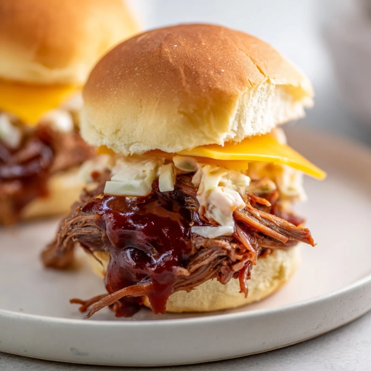 Freshly shredded beef brisket piled high on toasted slider buns, drizzled with smoky BBQ sauce for a messy, delicious bite.