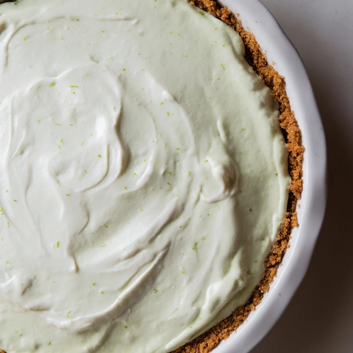 Bright green Key Lime Pie with Whipped Cream Topping showcases a smooth, tangy filling and fluffy whipped cream swirls.