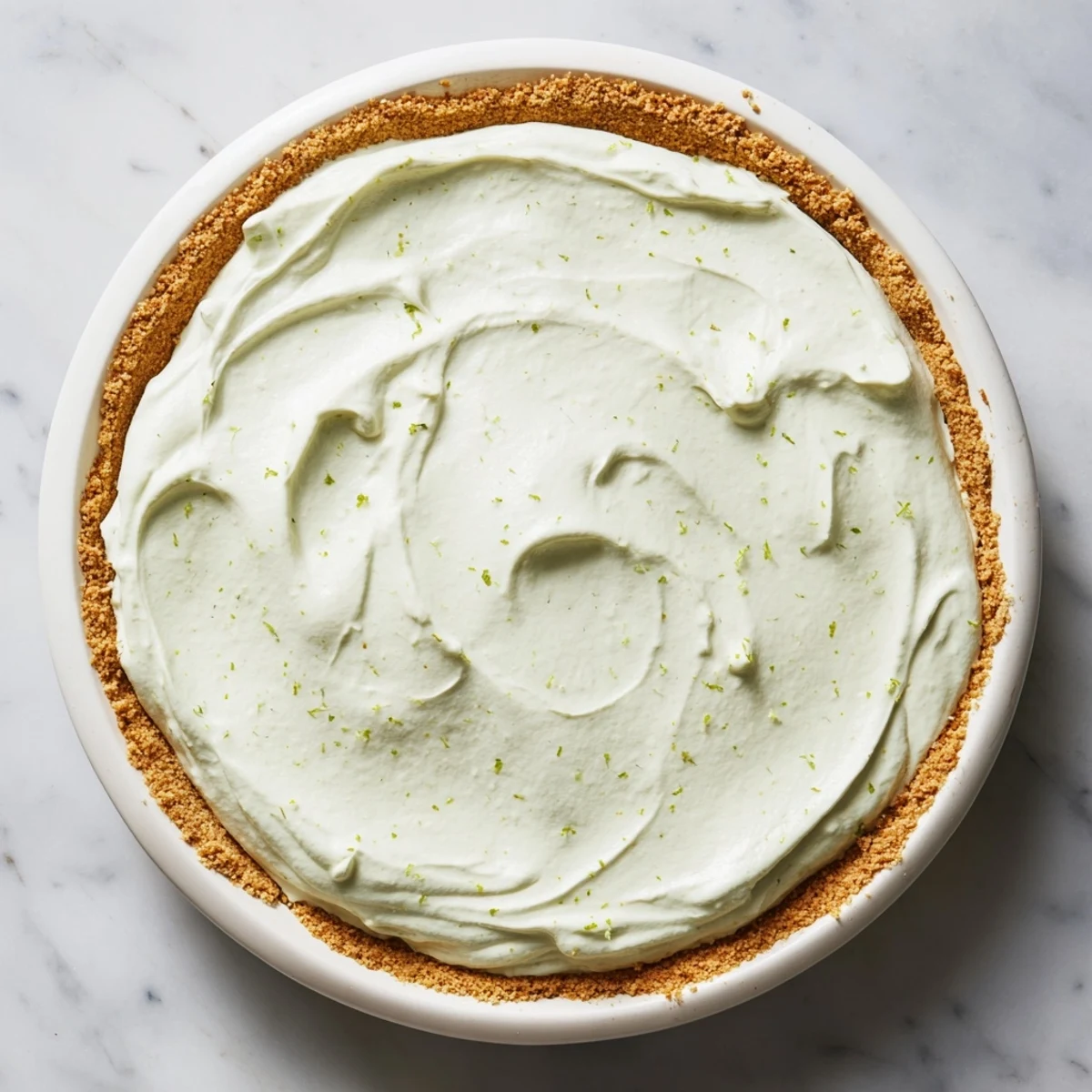 A chilled slice of Key Lime Pie with Whipped Cream Topping served on a white dessert plate with lime wedges.  