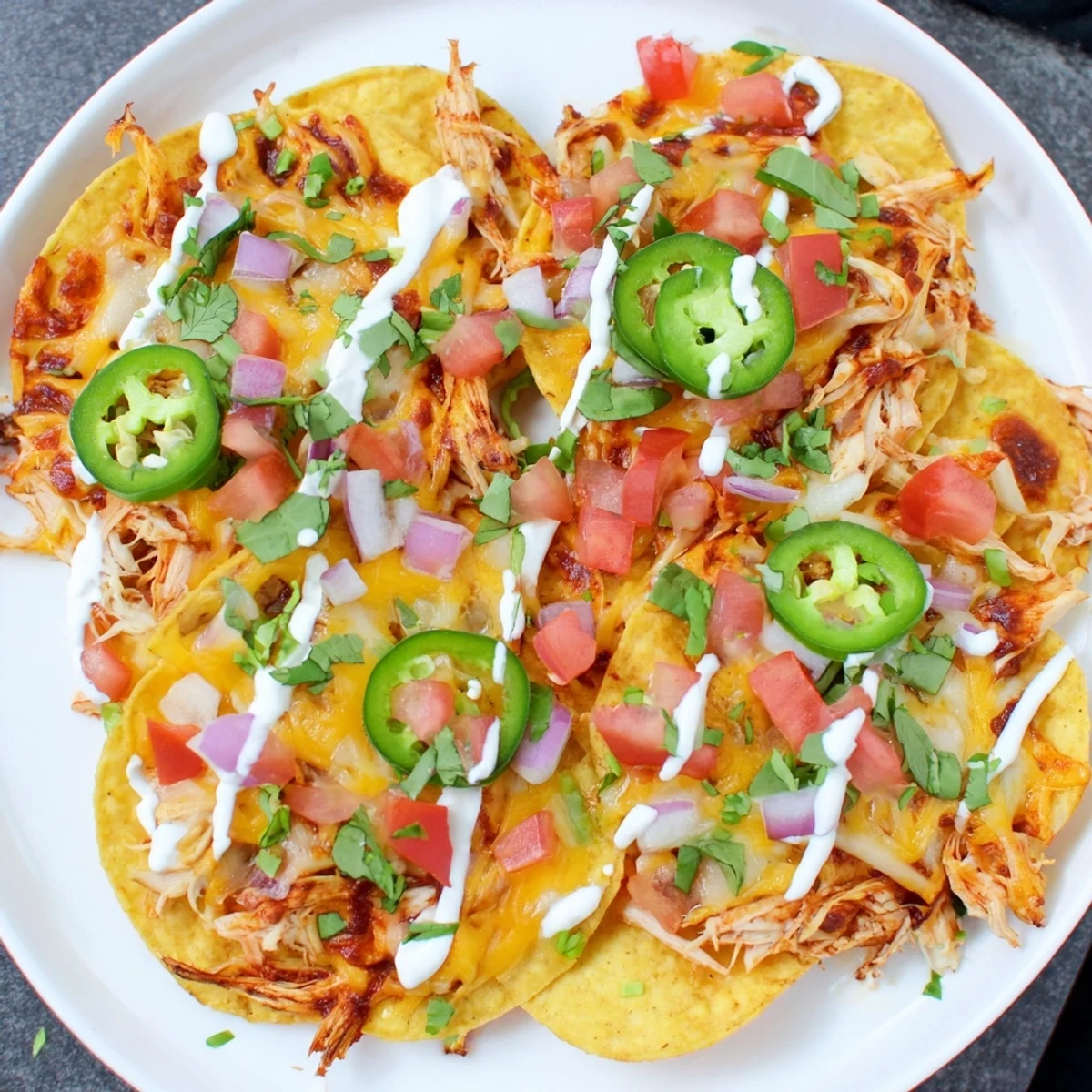 Crispy tortilla chips loaded with juicy pulled chicken and spicy jalapeños for a festive snack.