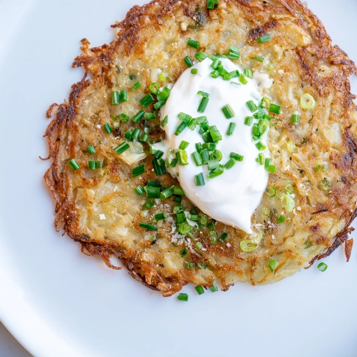 Close-up of golden-brown Potato Cakes with Scallions and Sour Cream showing fresh green scallions inside.