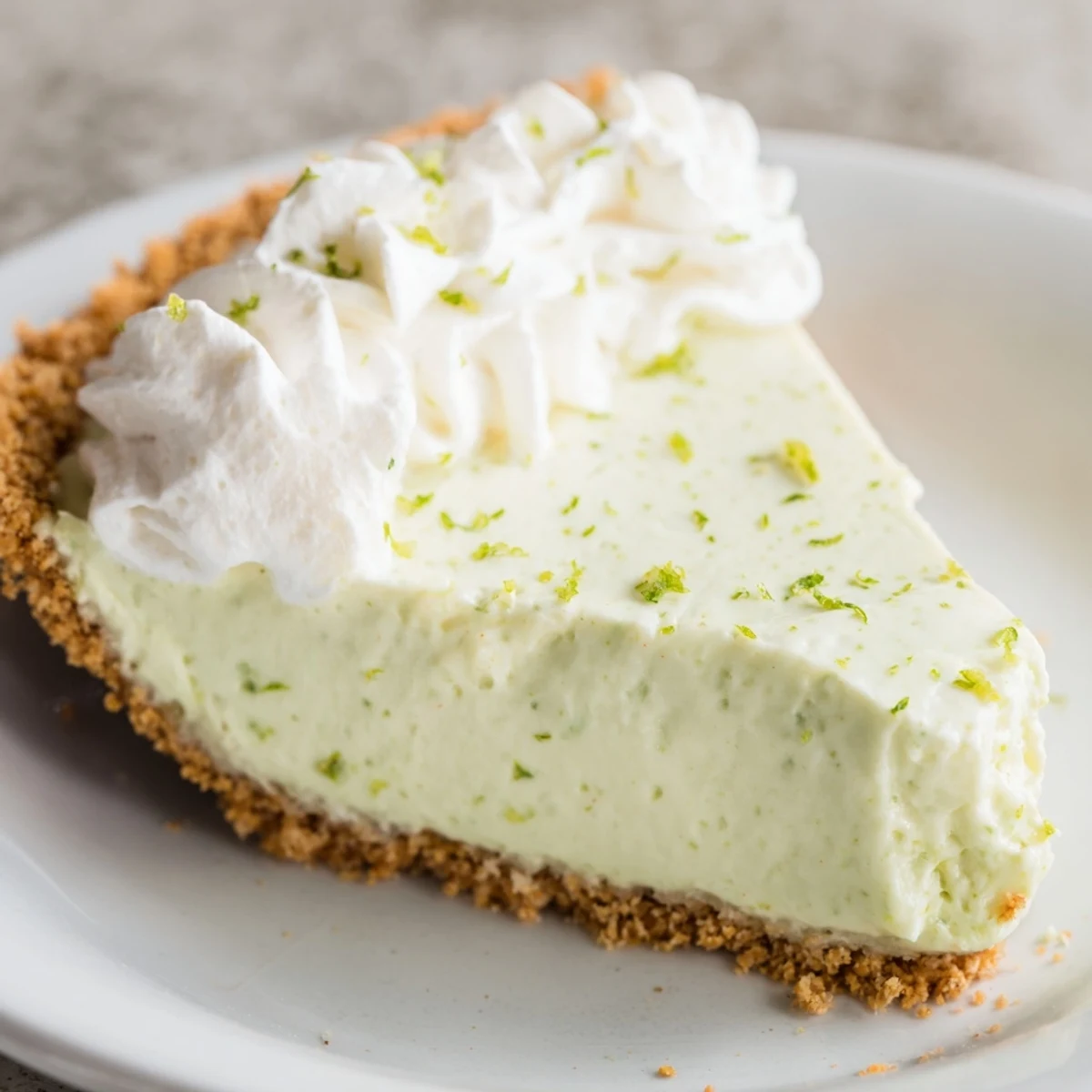 Key Lime Pie with Whipped Cream Topping showcases a creamy, tangy green filling inside a golden graham cracker crust.