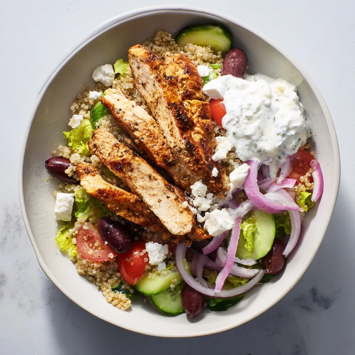 Brightly colored Greek Chicken Gyro Bowls with Tzatziki offer fresh cucumbers, tomatoes, and olives drizzled with creamy yogurt sauce.