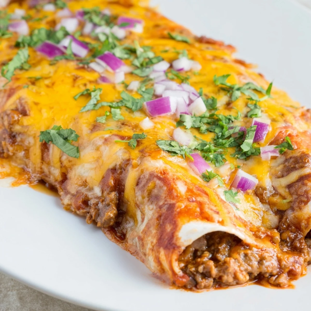 This Beef Enchiladas with Homemade Red Sauce recipe features tender tortillas filled with seasoned ground beef and sauce.