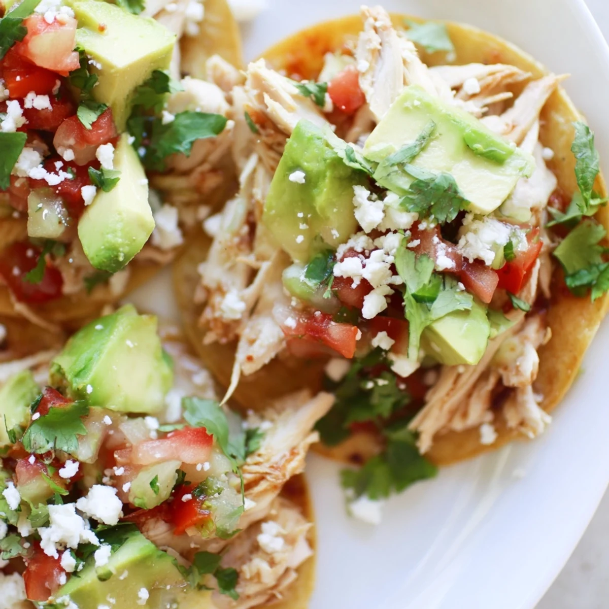 Plate of Mini Chicken Tostadas served with lime wedges and a drizzle of sour cream.
