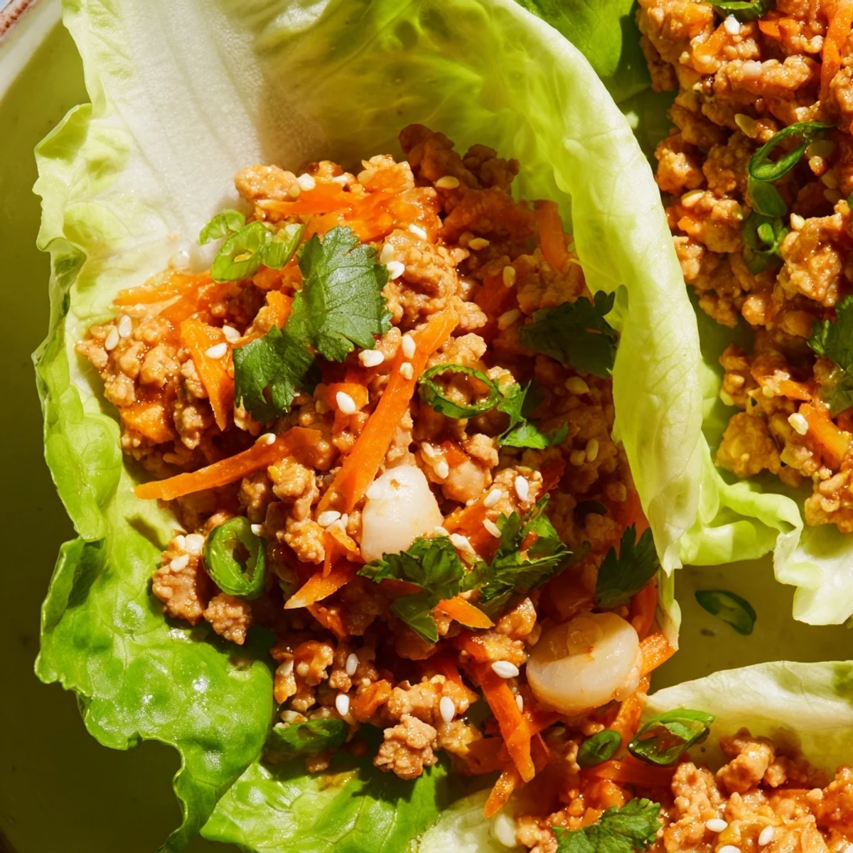 Crisp butter lettuce cups cradling savory ground chicken with ginger, garlic, and carrots for a fresh bite.  