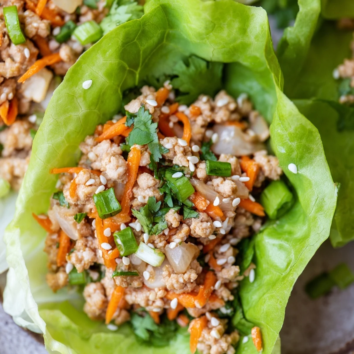 Tender potsticker chicken lettuce boats garnished with toasted sesame seeds and vibrant cilantro, ready to dip.  