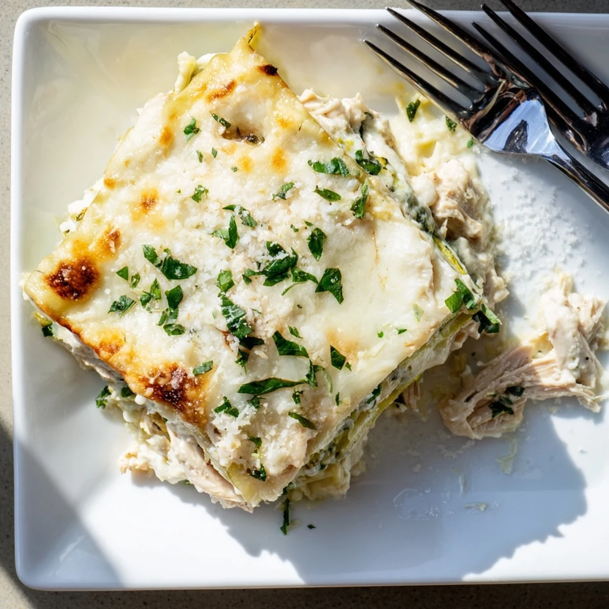 Close-up view of cheesy Chicken Alfredo Zucchini Lasagna with zucchini ribbons and creamy Alfredo sauce bubbling.