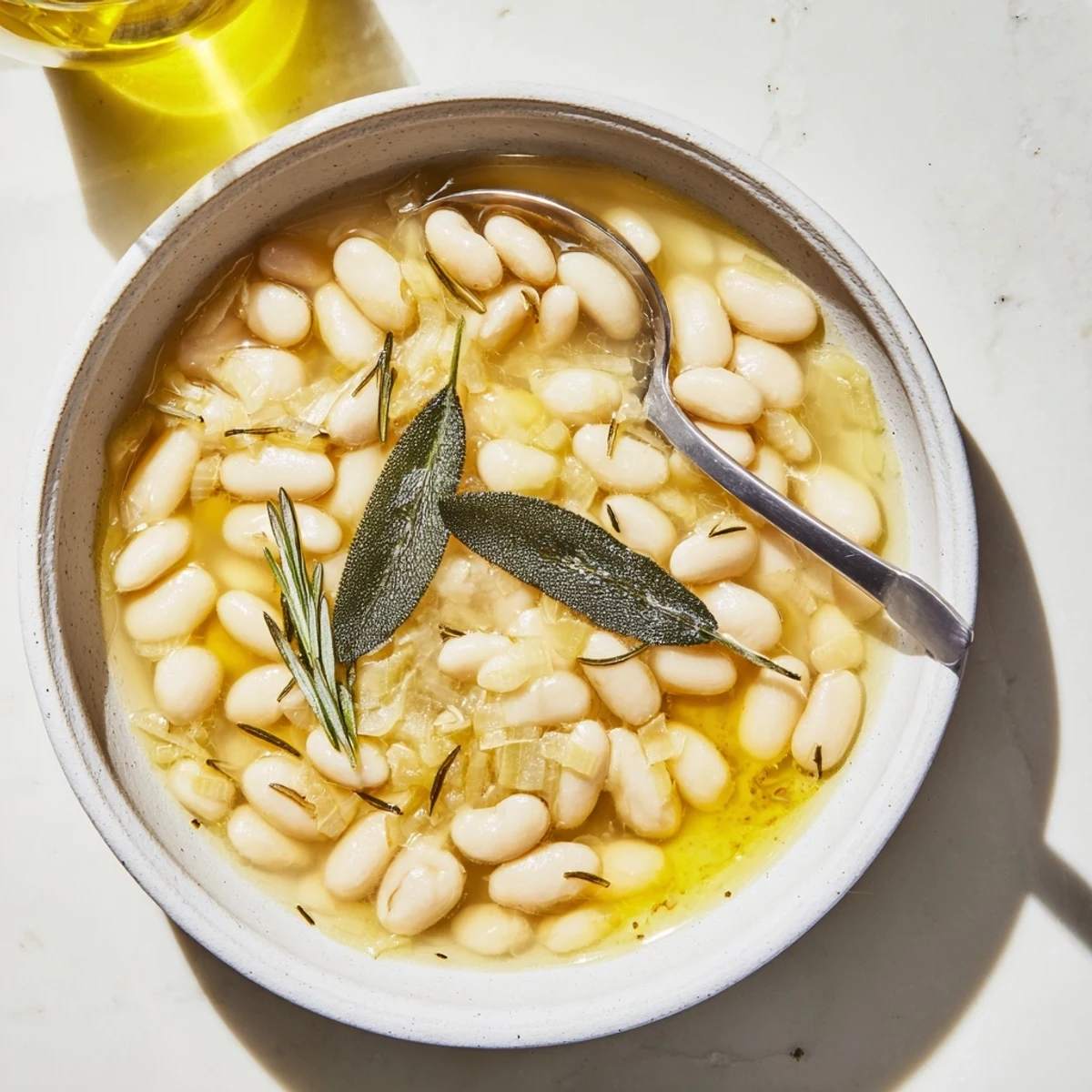 Warm Tuscan White Beans garnished with sage and red pepper flakes in an Italian kitchen.