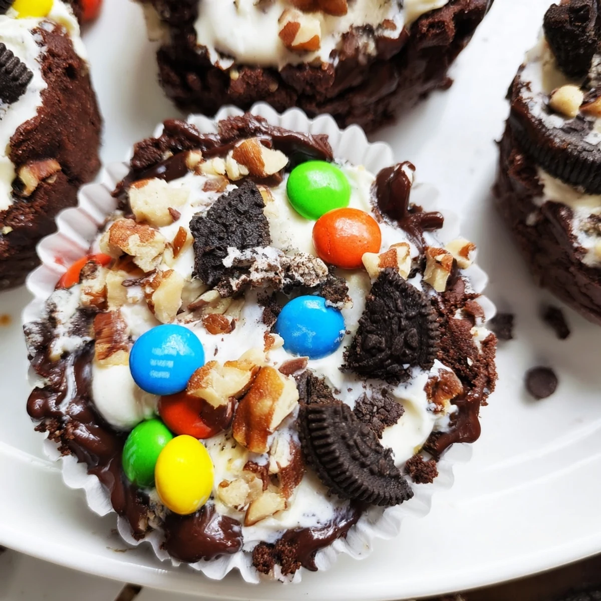 Rich loaded brownie cheesecake cups topped with colorful mini M&Ms and chopped pecans