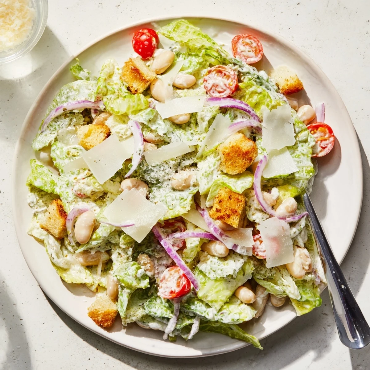 Fresh butter bean Caesar salad with crisp romaine, creamy dressing, and crunchy croutons in a white bowl.