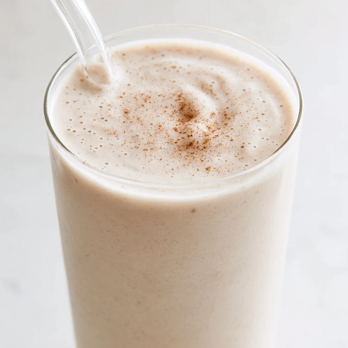 Thick and creamy Greek yogurt banana smoothie poured into a tall glass with banana slice garnish
