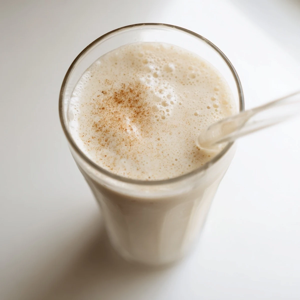Golden Greek yogurt banana smoothie with ice cubes swirling against a bright kitchen backdrop