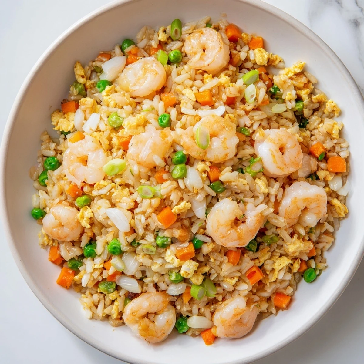 Golden platter of authentic shrimp fried rice topped with fresh green onions and colorful vegetables