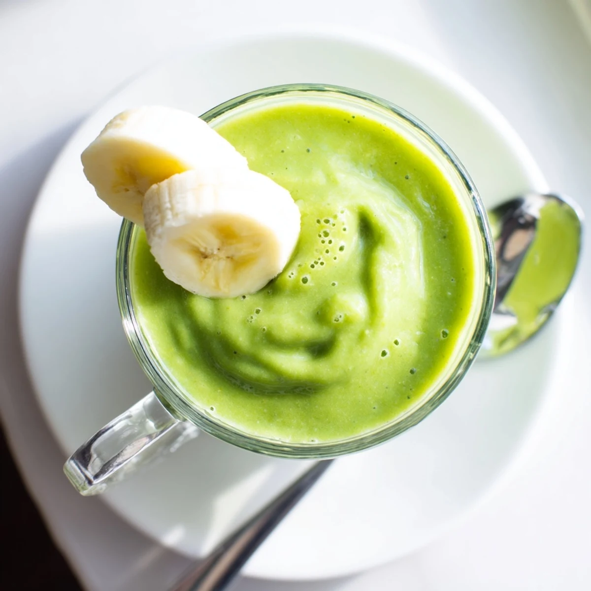 Vibrant green smoothie made with Greek yogurt, banana, and spinach poured into a tall glass