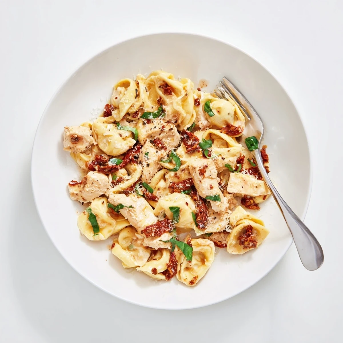Golden chicken and cheese tortellini simmering in a rich Italian-American cream sauce with sun-dried tomato pieces