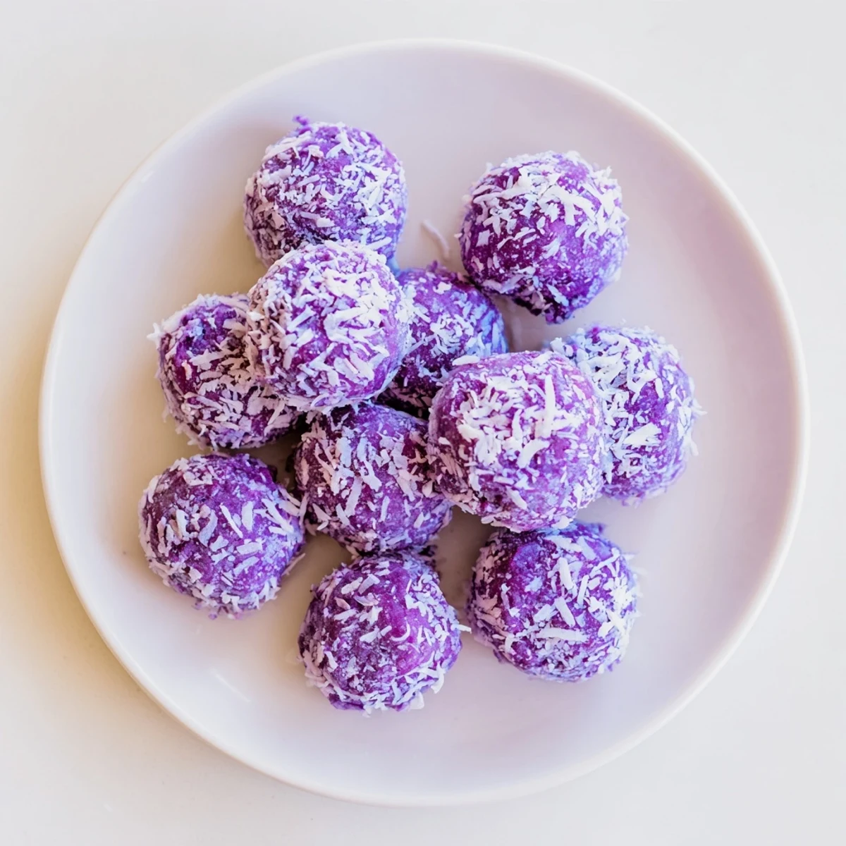 Golden Coconut Ube Besito Cookies arranged on a white platter with shredded coconut coating