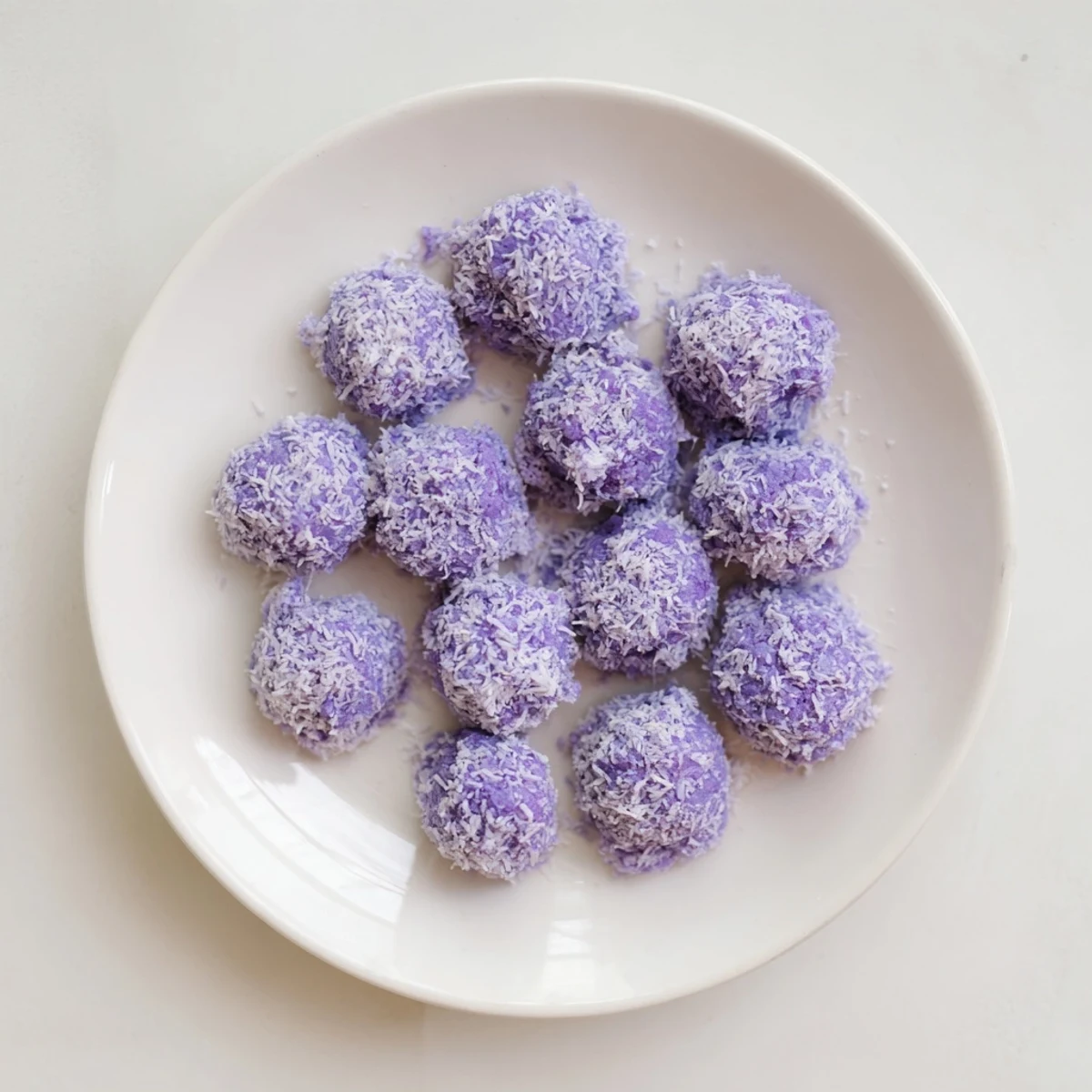 Vibrant purple Coconut Ube Besito Cookies stacked on a wooden board with afternoon tea