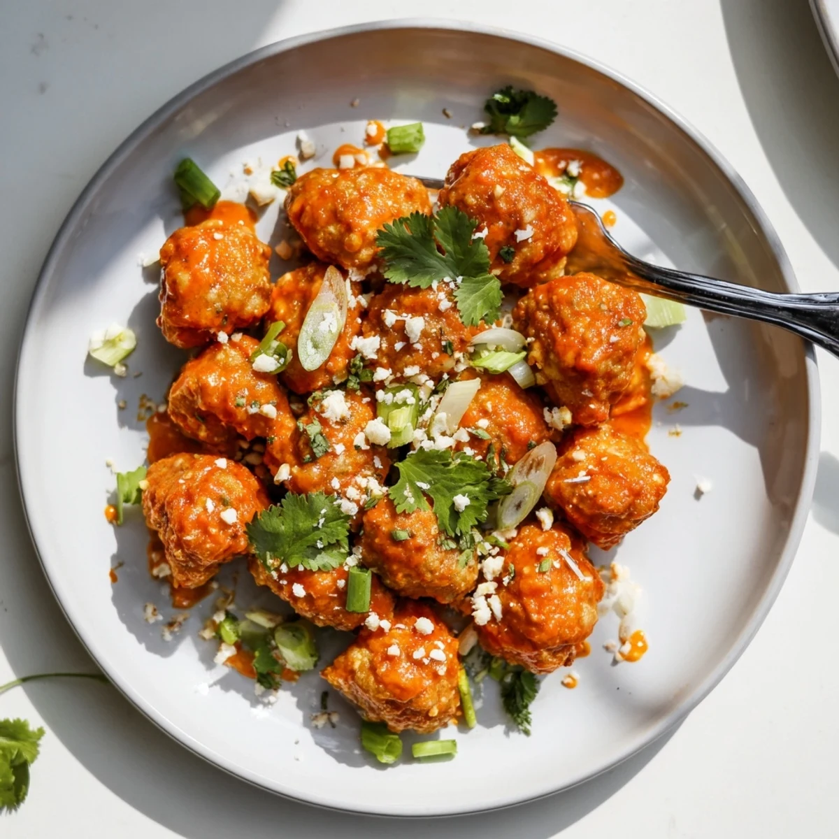 Plate of spicy Bang Bang Chicken garnished with scallions and toasted sesame