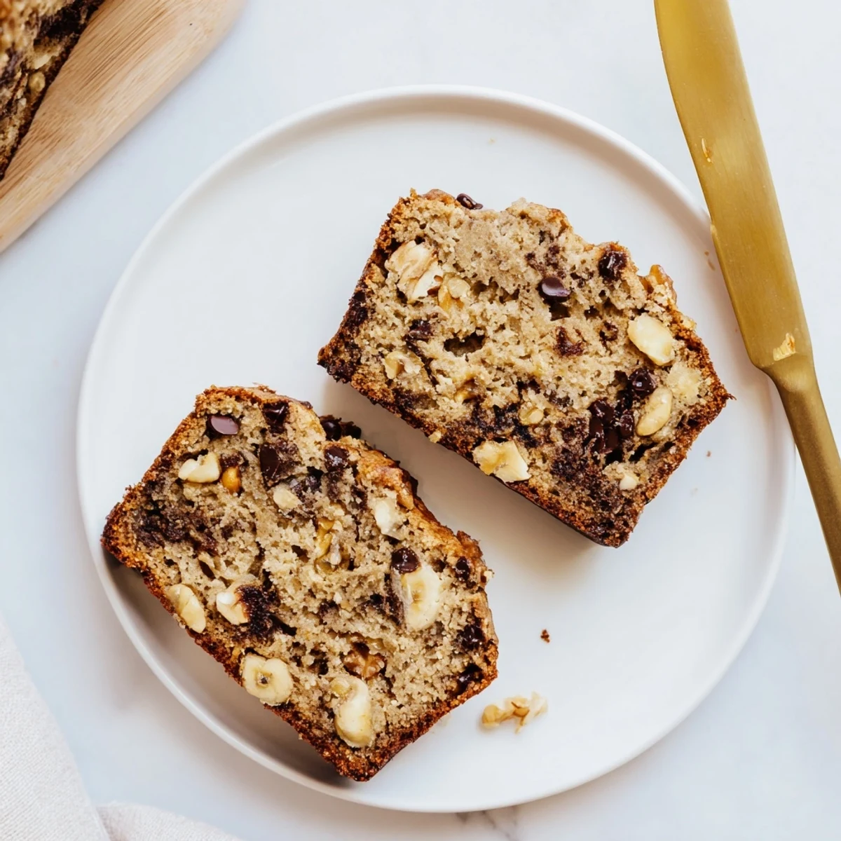 Thick slice of tender banana bread with sour cream topped with melting butter on white plate