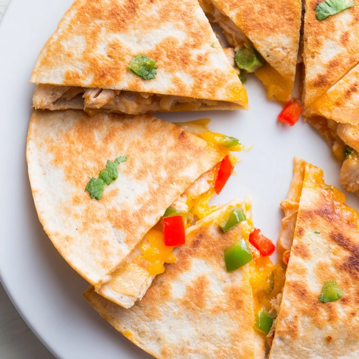 Golden chicken quesadillas sliced into wedges with melted cheddar and colorful bell peppers