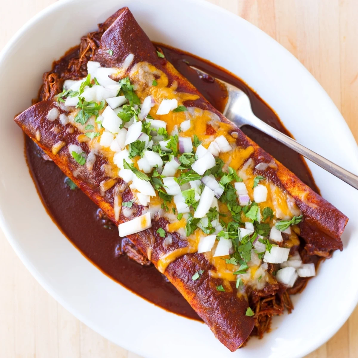 Baked birria enchiladas topped with melted Oaxaca cheese and fresh cilantro garnish