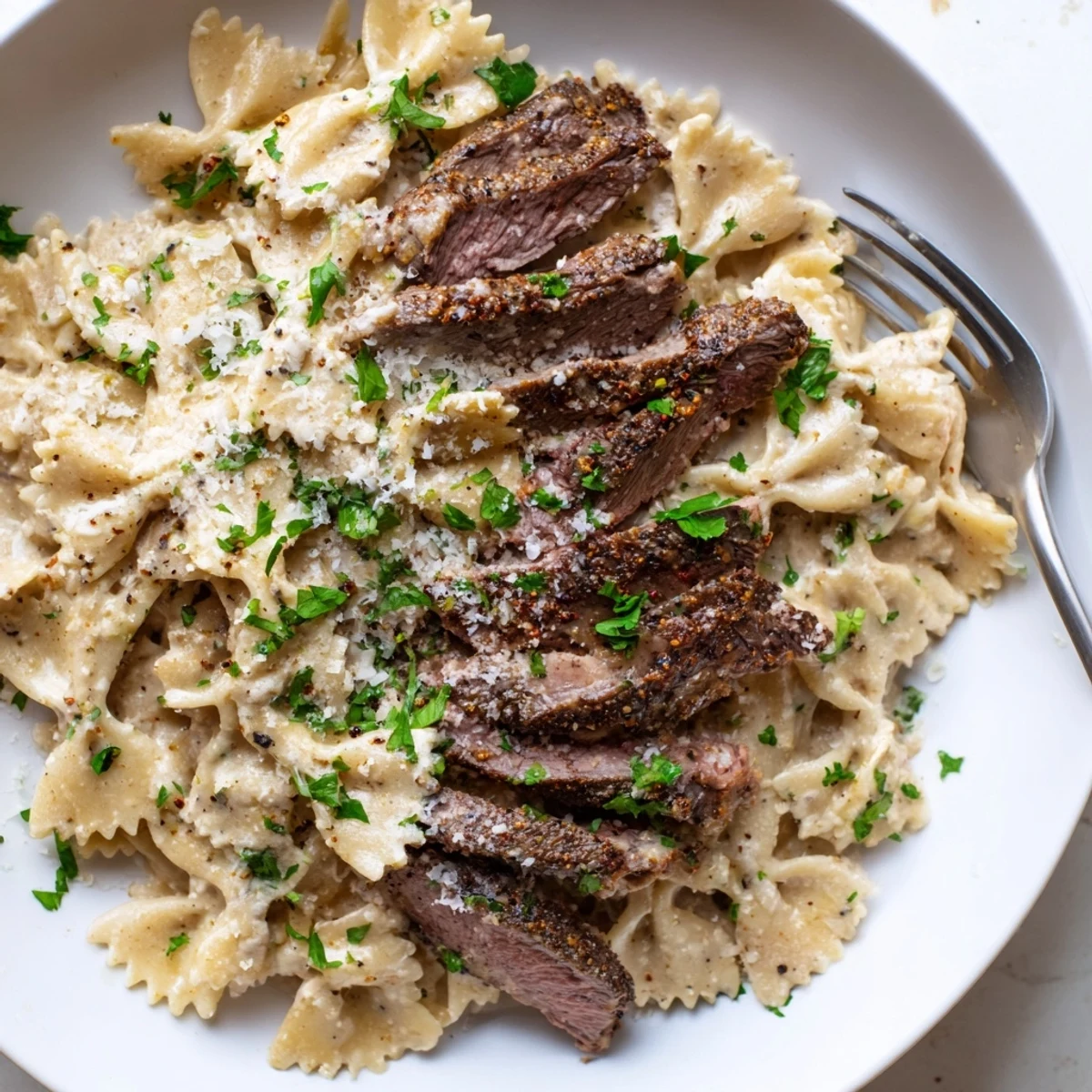 Hearty Cajun cream cheese Alfredo bowties featuring tender pasta and savory spiced beef on a white plate