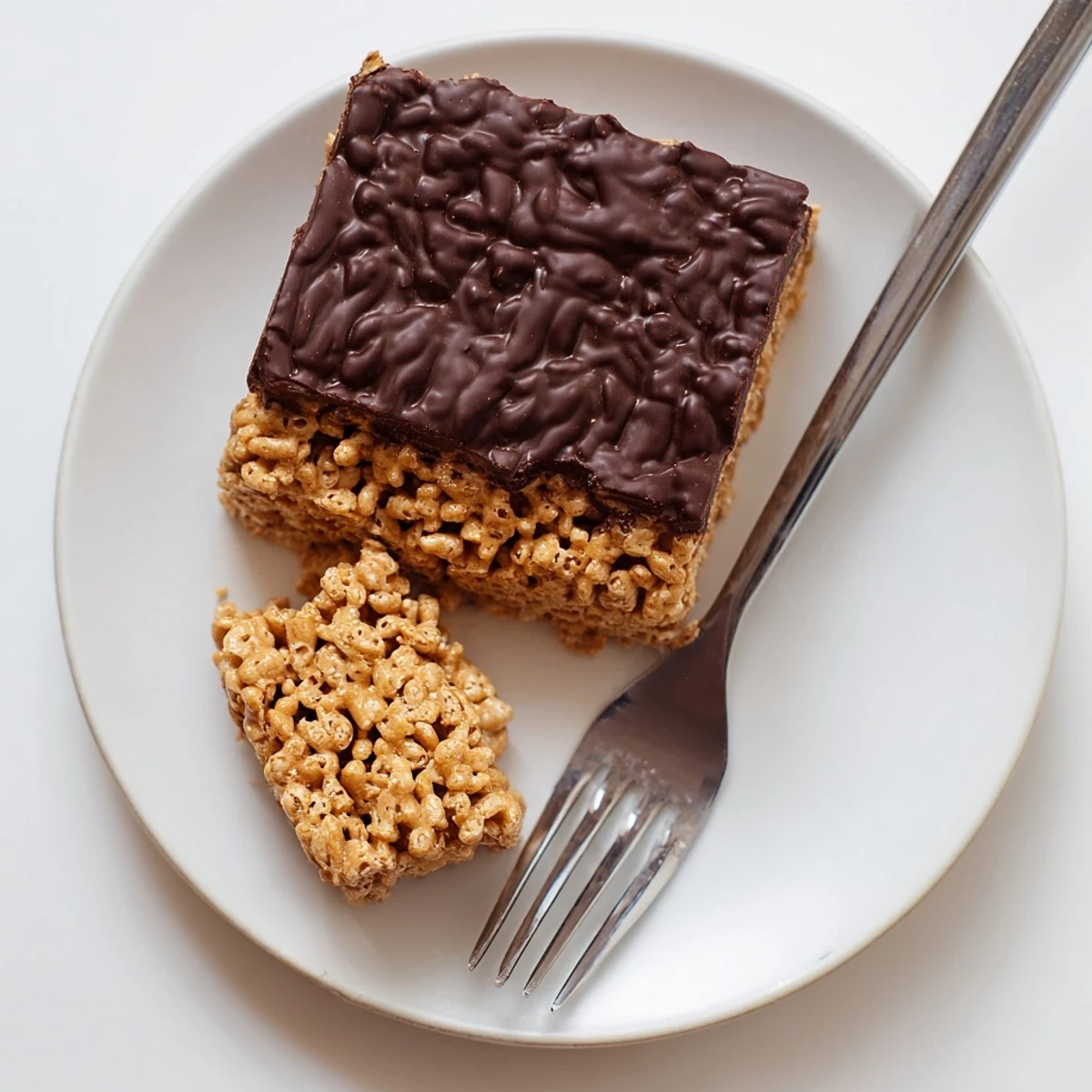 Homemade no-bake honey Chex chocolate peanut butter bars stacked on a decorative platter with a glass of milk