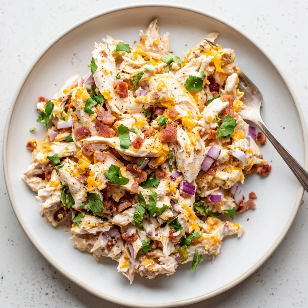 Jalapeno popper chicken salad featuring tender shredded chicken, spicy peppers, and smoky bacon crumbles on a rustic wooden board