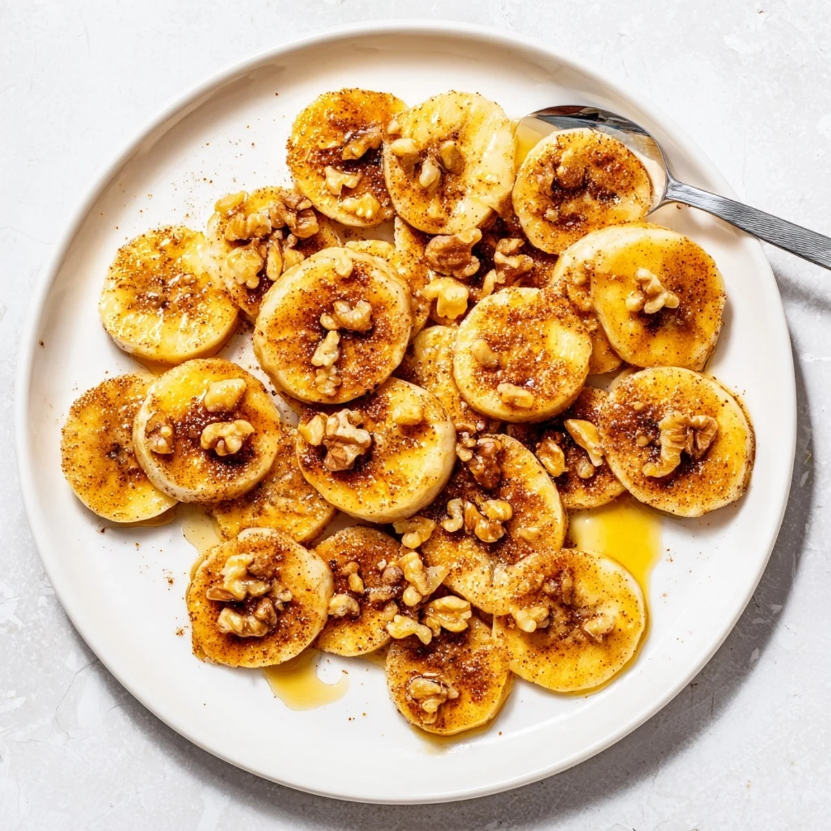 Perfectly fried cinnamon bananas arranged on a white plate, ready to serve with optional honey drizzle