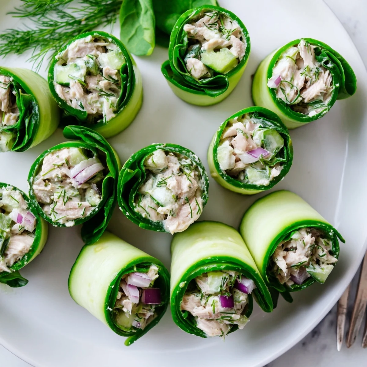 Low carb chicken salad cucumber roll ups arranged on a white serving platter