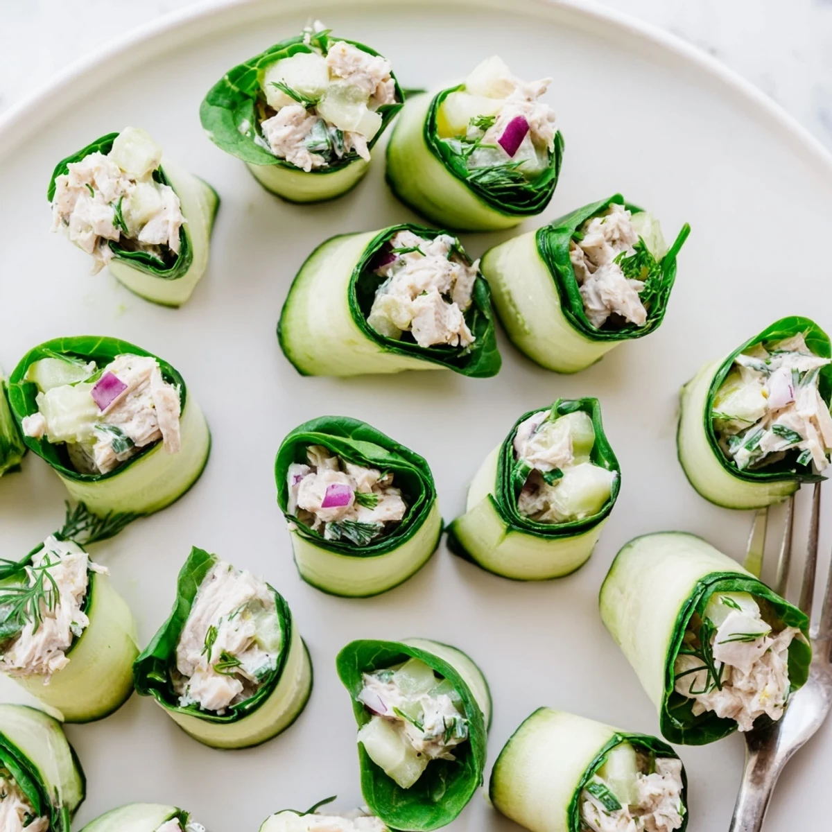 Green cucumber slices spiraled around dill chicken salad mixture, perfect healthy snack bites