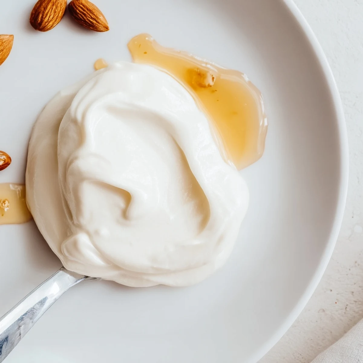 Thick and creamy homemade Greek yogurt topped with fresh honey, walnuts, and berries in a white ceramic bowl