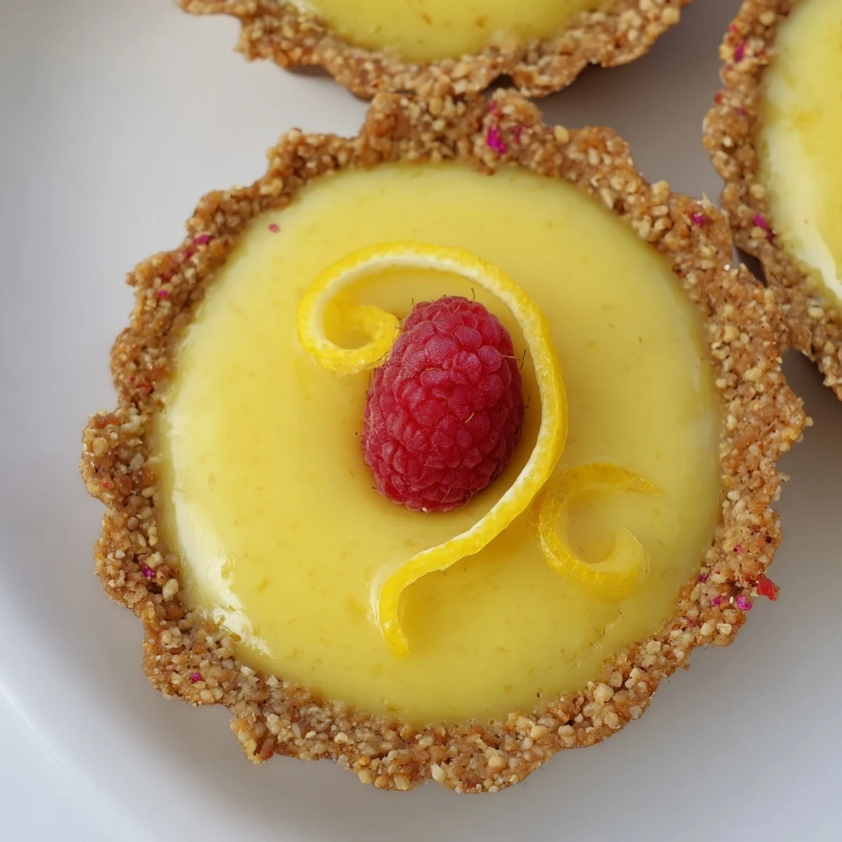 Silky mini vegan lemon tarts dusted with lemon zest arranged on a serving platter