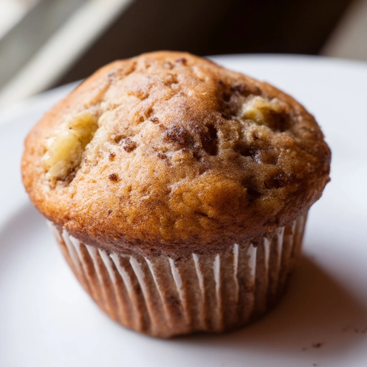 Soft banana muffins nestled in paper liners dusted with warm cinnamon