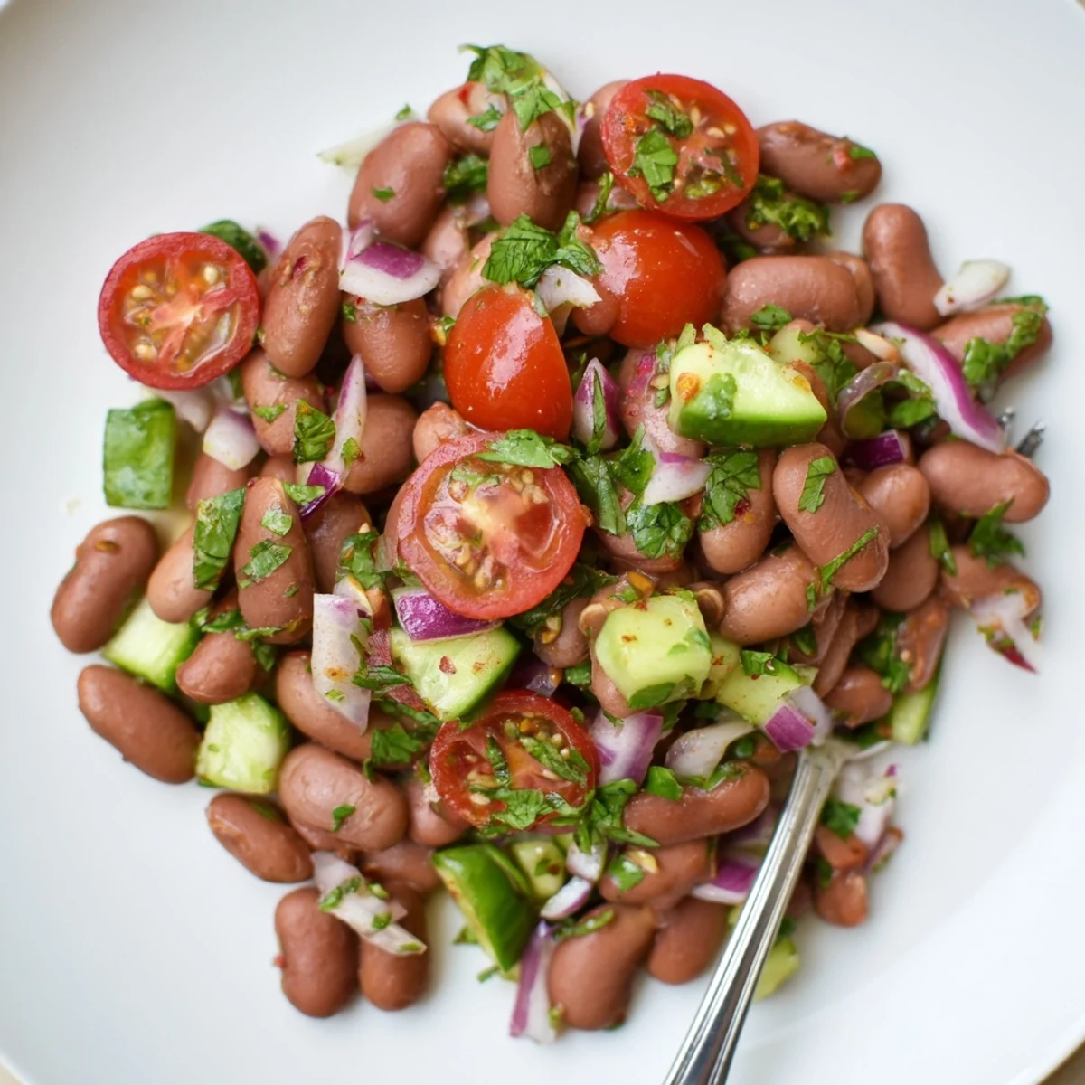 Colorful pinto bean salad tossed with crisp veggies and bright lime dressing in a rustic bowl