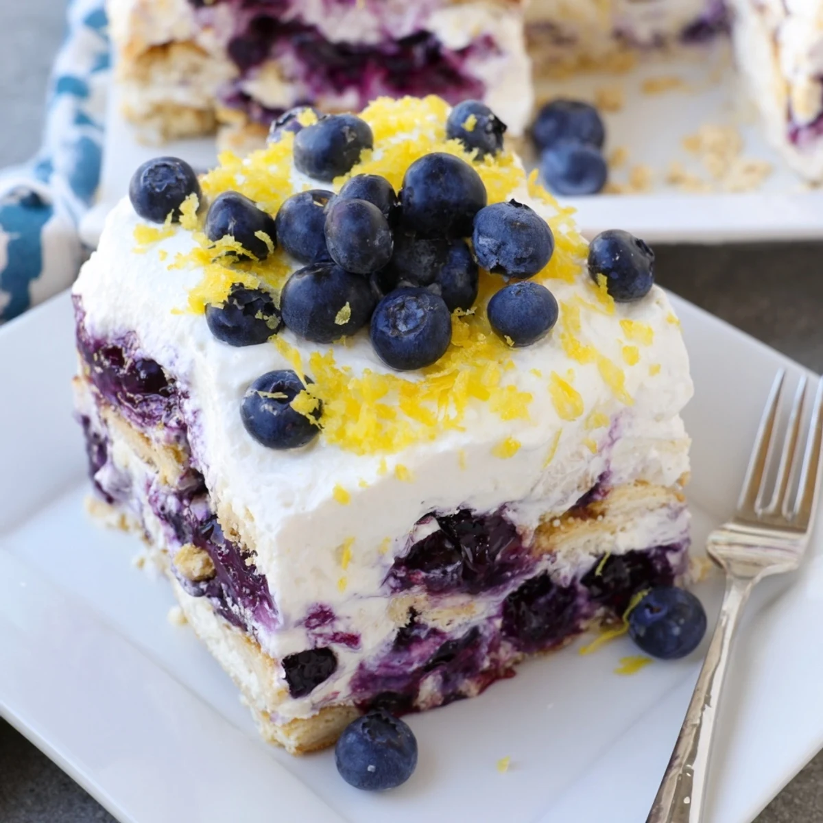 A square of chilled lemon blueberry lasagna served on a white dessert plate