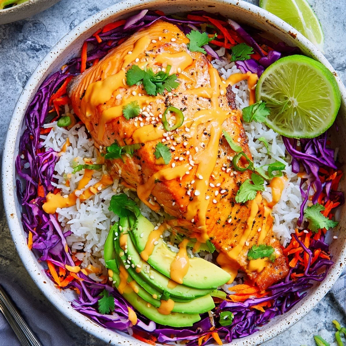 Homemade Bang Bang Salmon Bowls Recipe plated with avocado slices, cilantro, lime