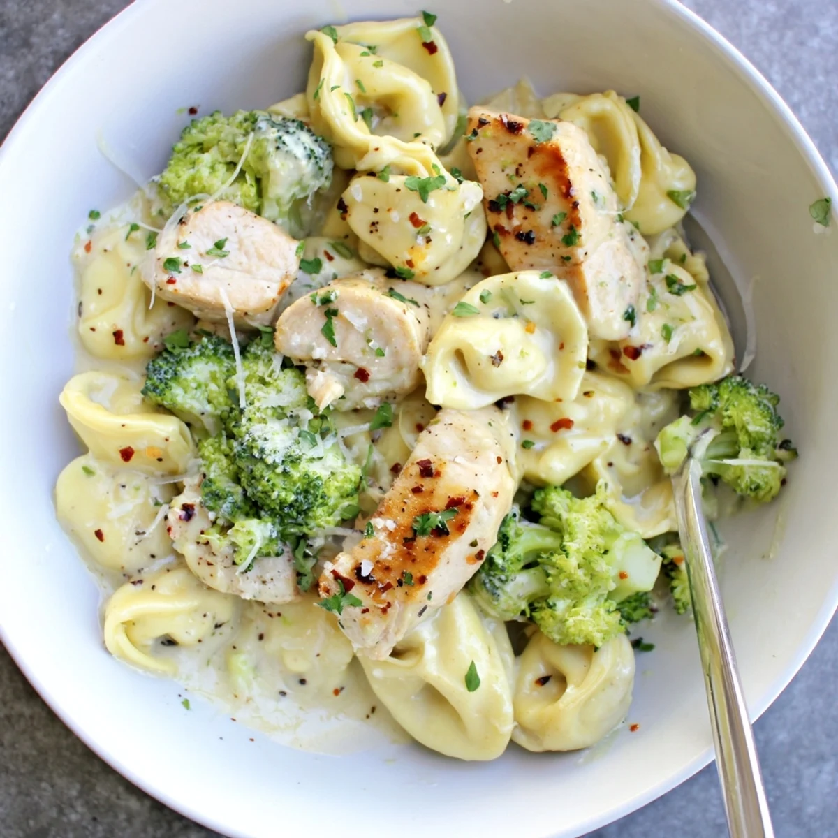 Skillet of Creamy Garlic Parmesan Tortellini Chicken Broccoli Recipe with golden seared chicken bites
