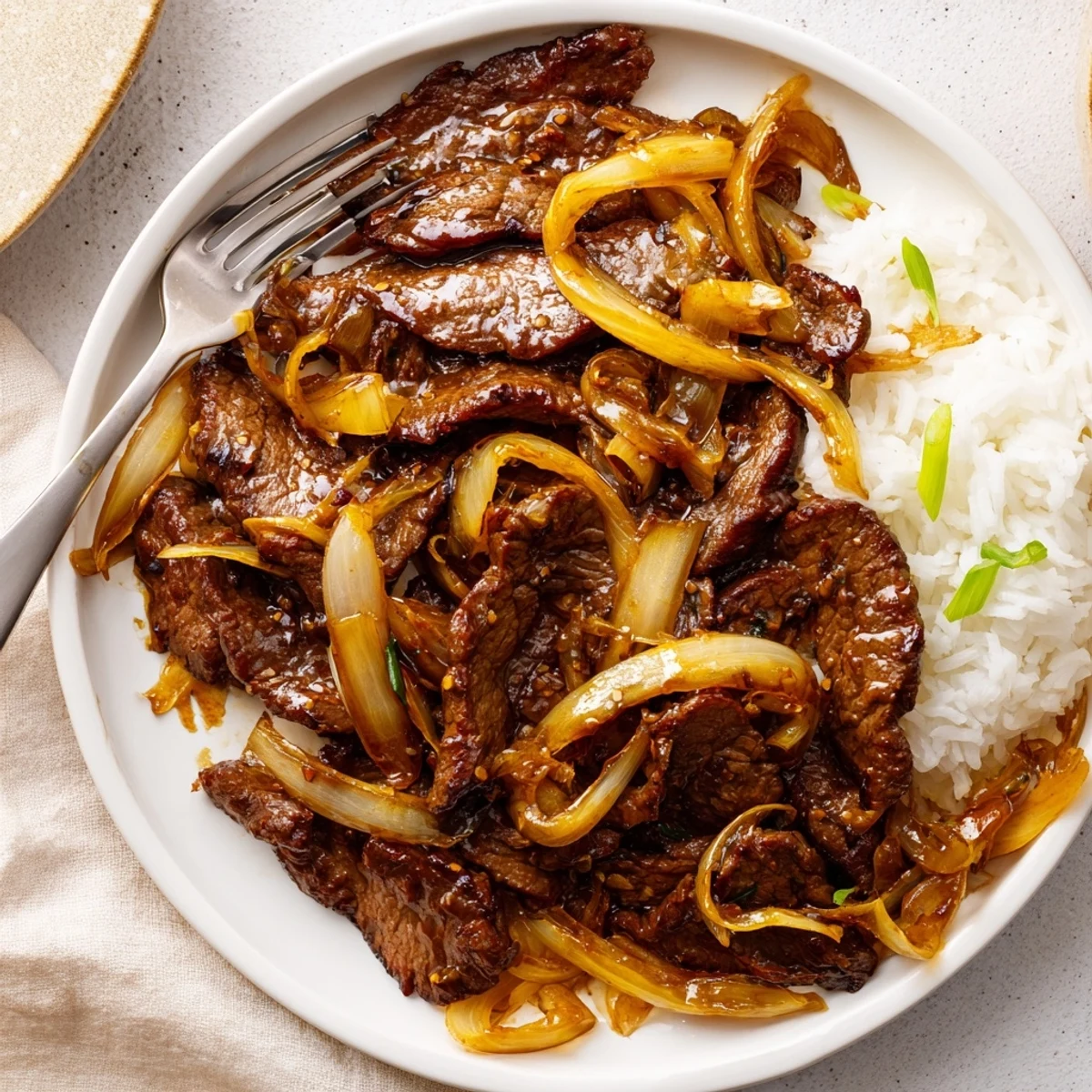 Sizzling wok full of thin steak slices in Crispy Beef and Onion Stir Fry.