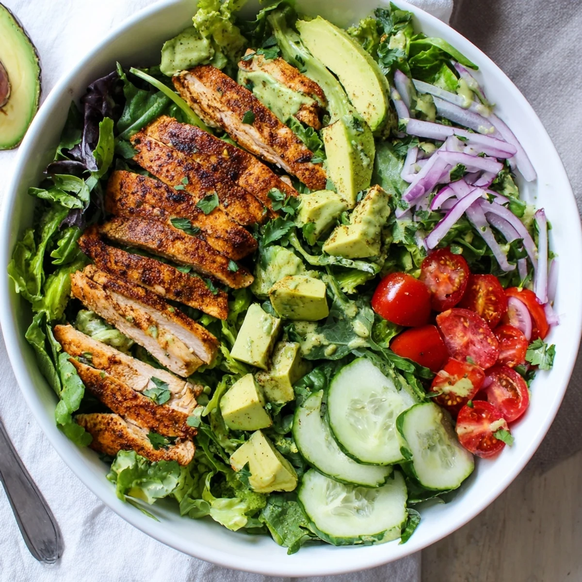 Colorful creamy avocado grilled chicken salad bowl with fresh vegetables and tangy dressing