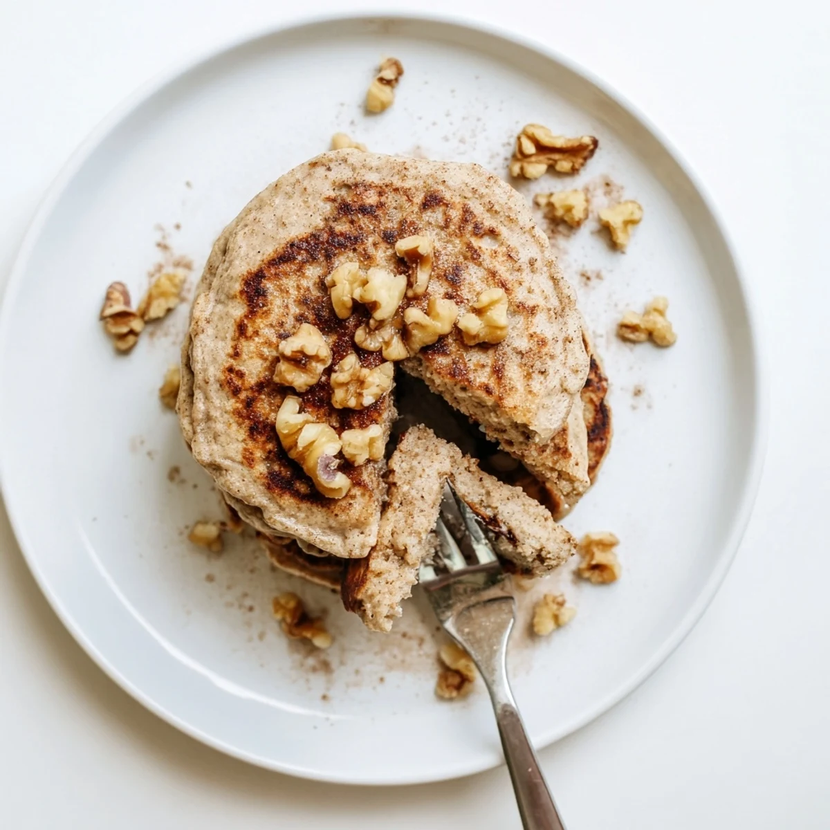 Golden brown protein banana pancakes cooking in a skillet with bubbles forming on the surface