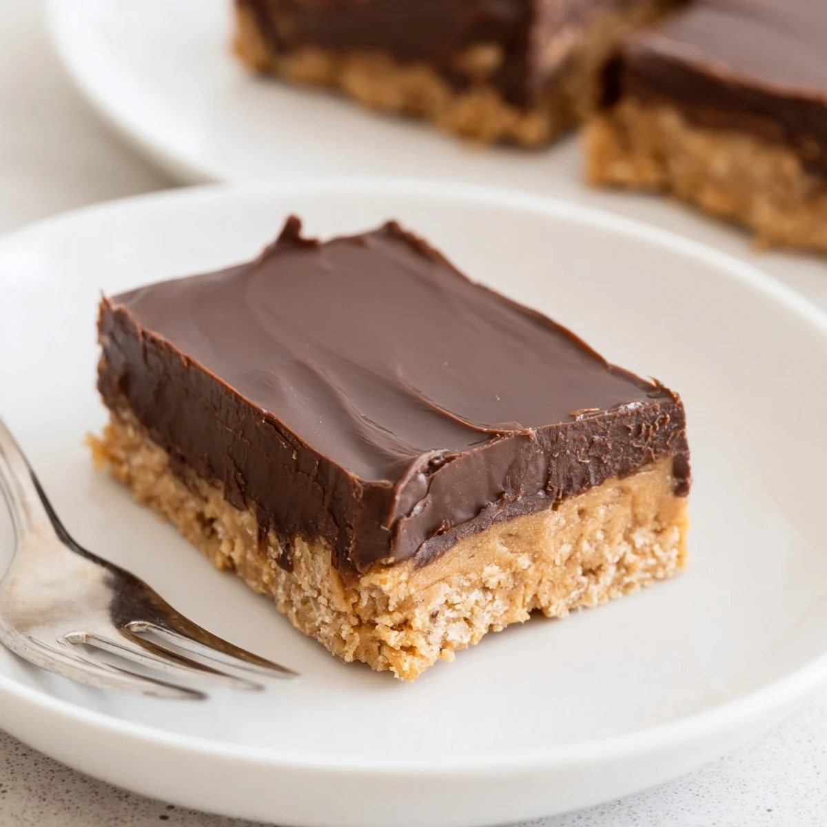 Peanut Butter Bars cooling on parchment, glossy chocolate topping and nutty crumbs