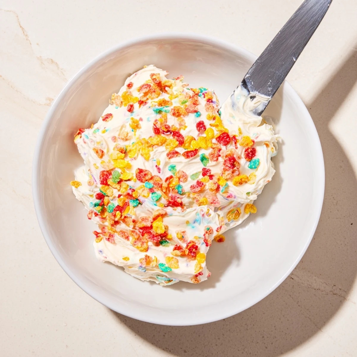 Whipped Fruity Pebbles Cereal Frosting spread on vanilla cake, sweet aroma