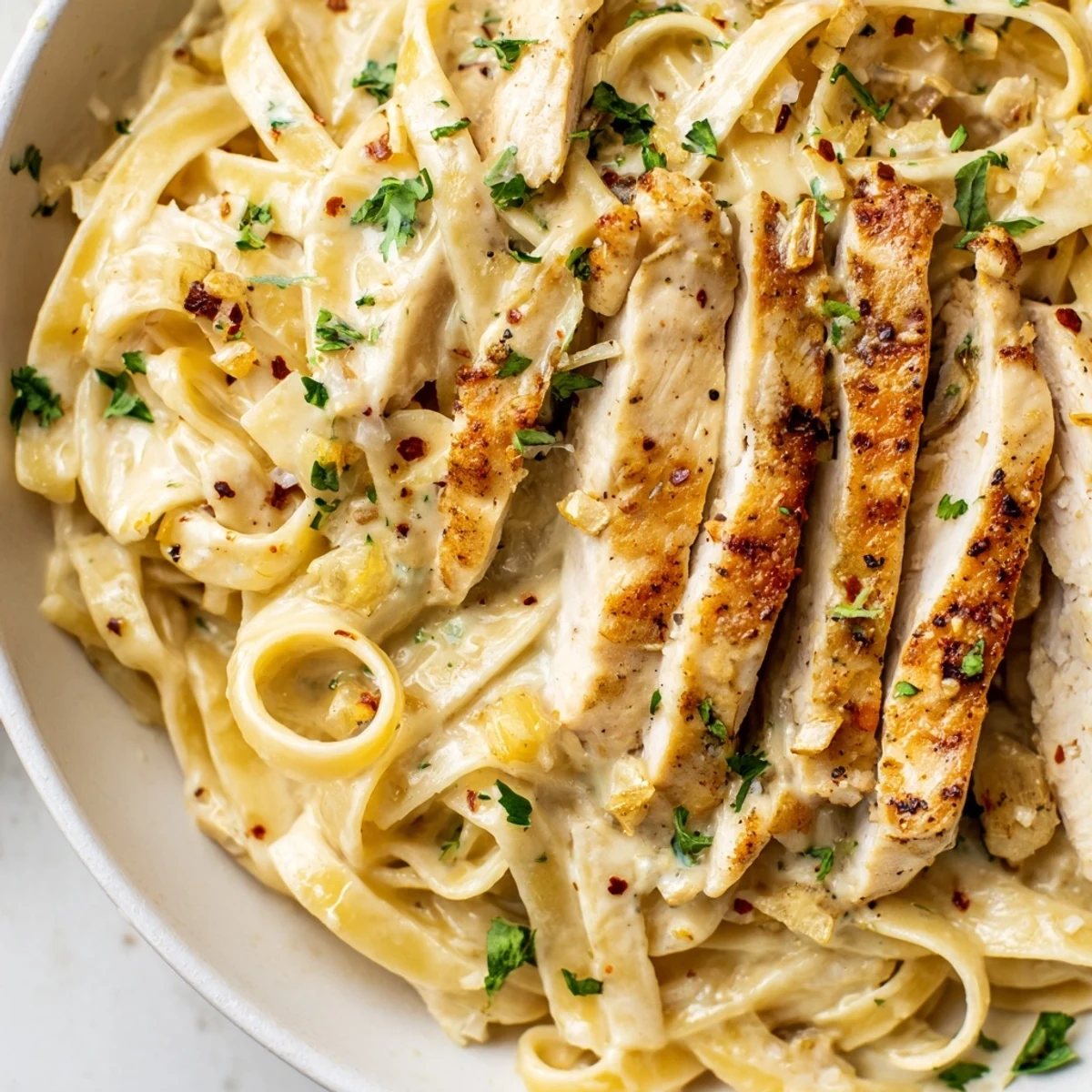 Creamy Garlic Parmesan Chicken Pasta in a white bowl with fresh parsley garnish